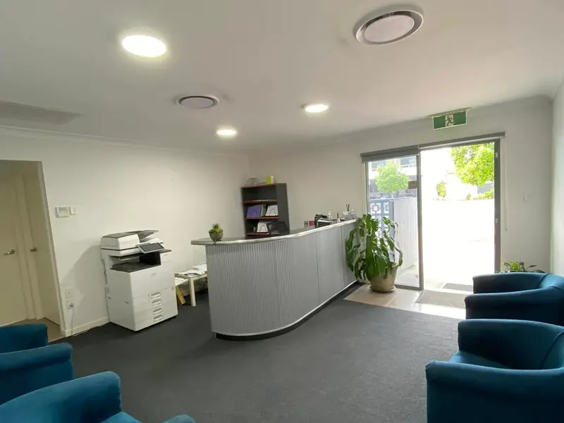 Reception and waiting area of a business with downlights and armchairs