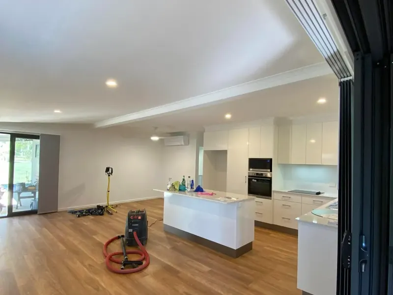 Open-plan kitchen and living area of a finished home lit by recessed downlights
